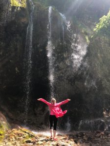 woman absorbing cleansing energy of waterfall