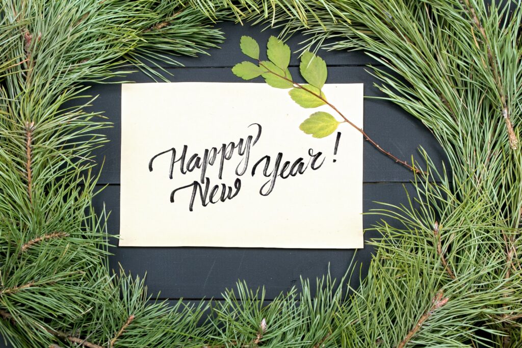 Wreath of evergreens surrounding a hand written note that says "Happy New Year!"