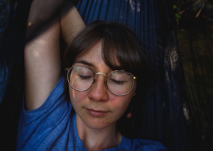 Lady in a blue top relaxing in a hammock while experiencing "Akashic Stillness"