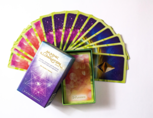 The Akashic Illumination Deck box is opened and spread out behind it are the different card backs for the three Akashic activities. Inside the box you can see the Akashic Infusions card back. 