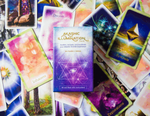 Card from the Akashic Illumination Deck spread out with the card deck box centered on top.