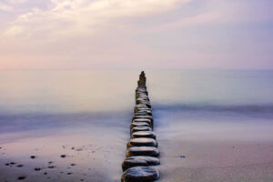 Introspective photo of a straight line of stepping stones going out into water.