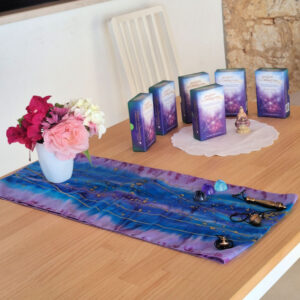 A Display of the Akashic Illumination Deck on a table with a silk scarf and vase of flowers from the Farm in Portugal